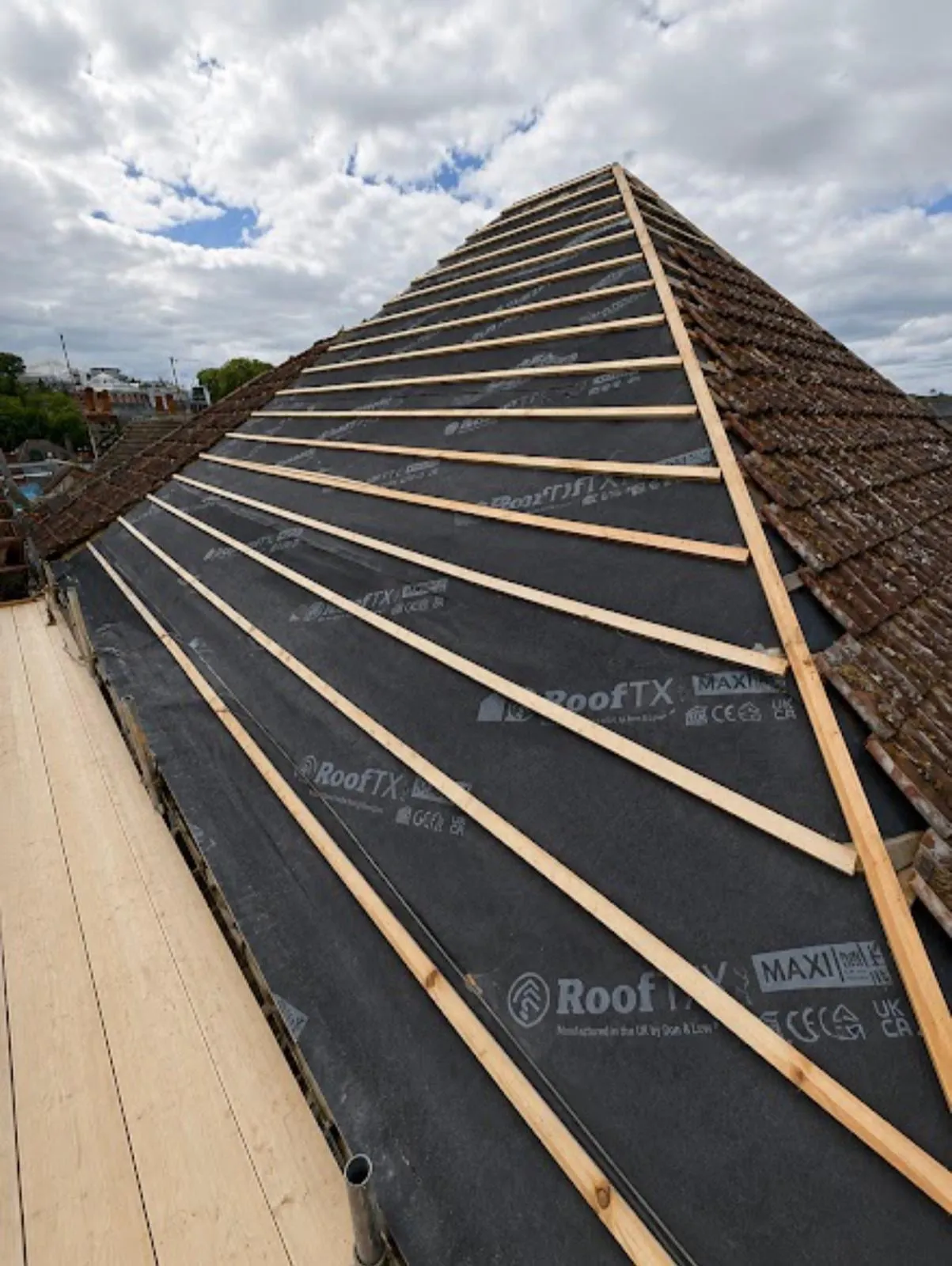 Battens fixed over membrane on a hipped roof, with new tiles starting at the eaves