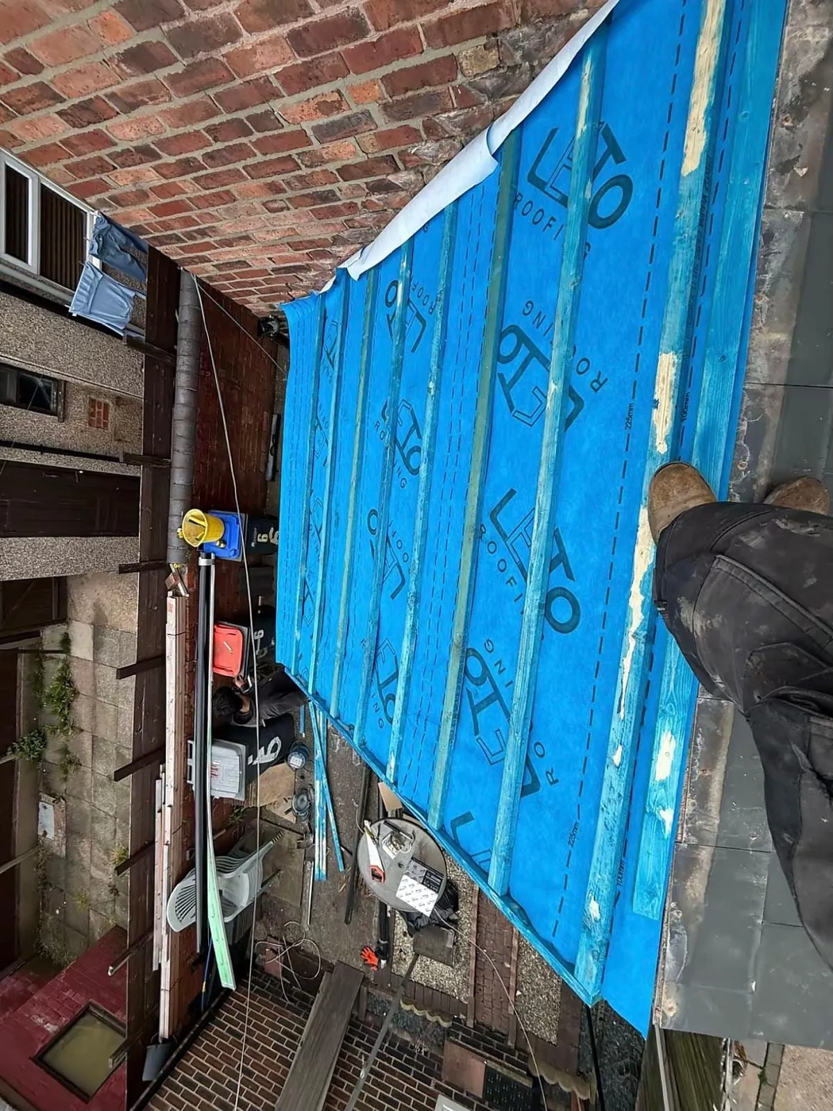 Blue membrane laid up against a brick wall during a re-roof
