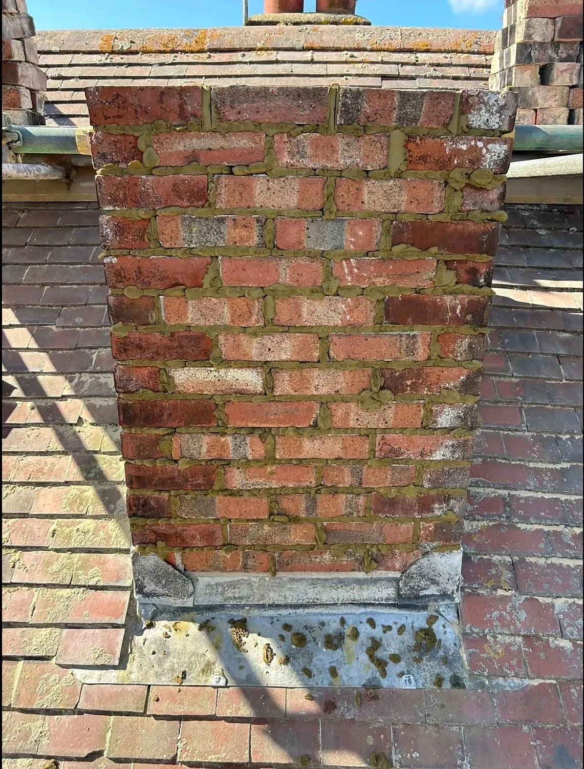 Chimney base with lead flashing and brickwork on a tiled roof