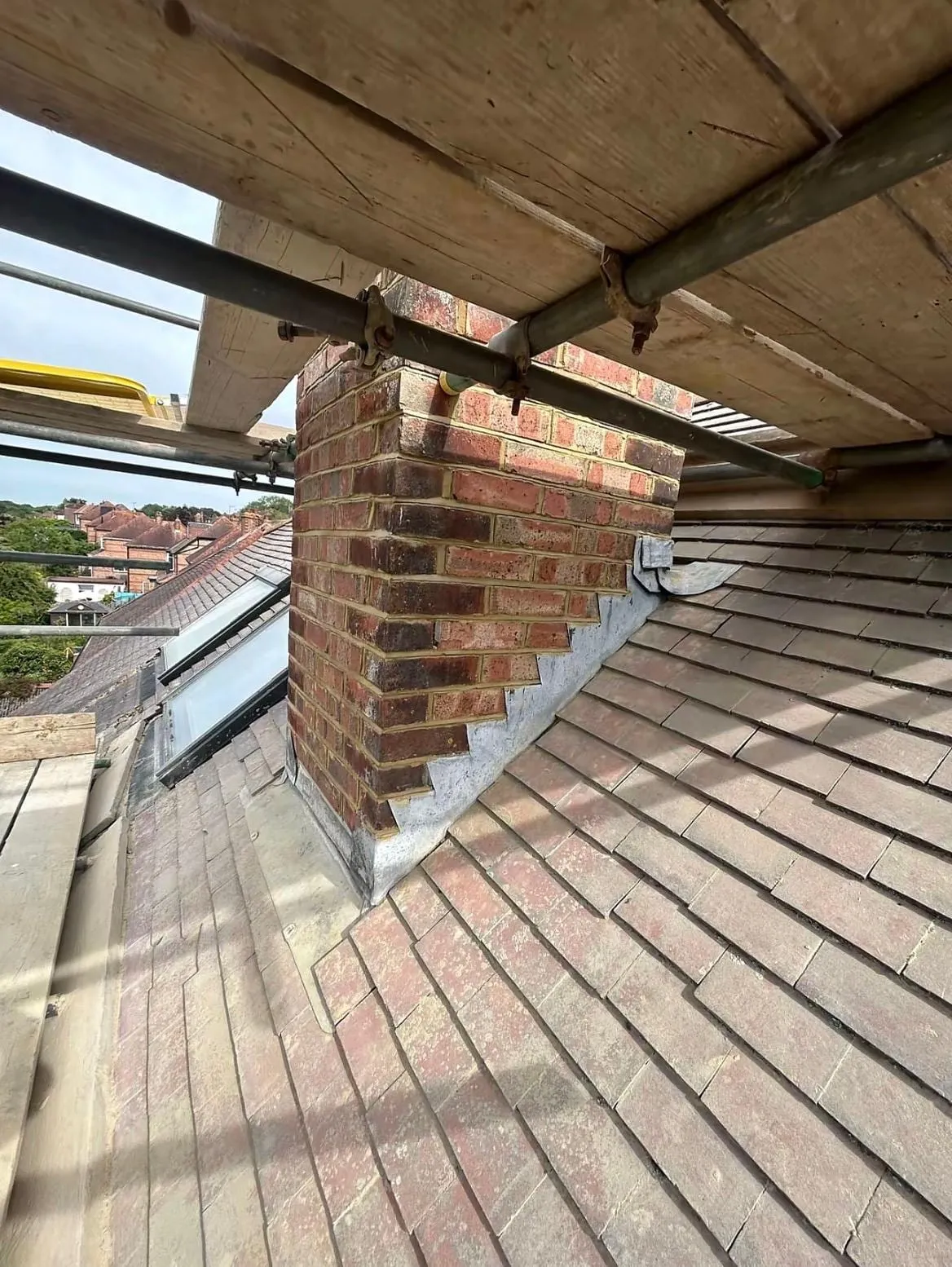Chimney with a lead apron seen through the scaffold