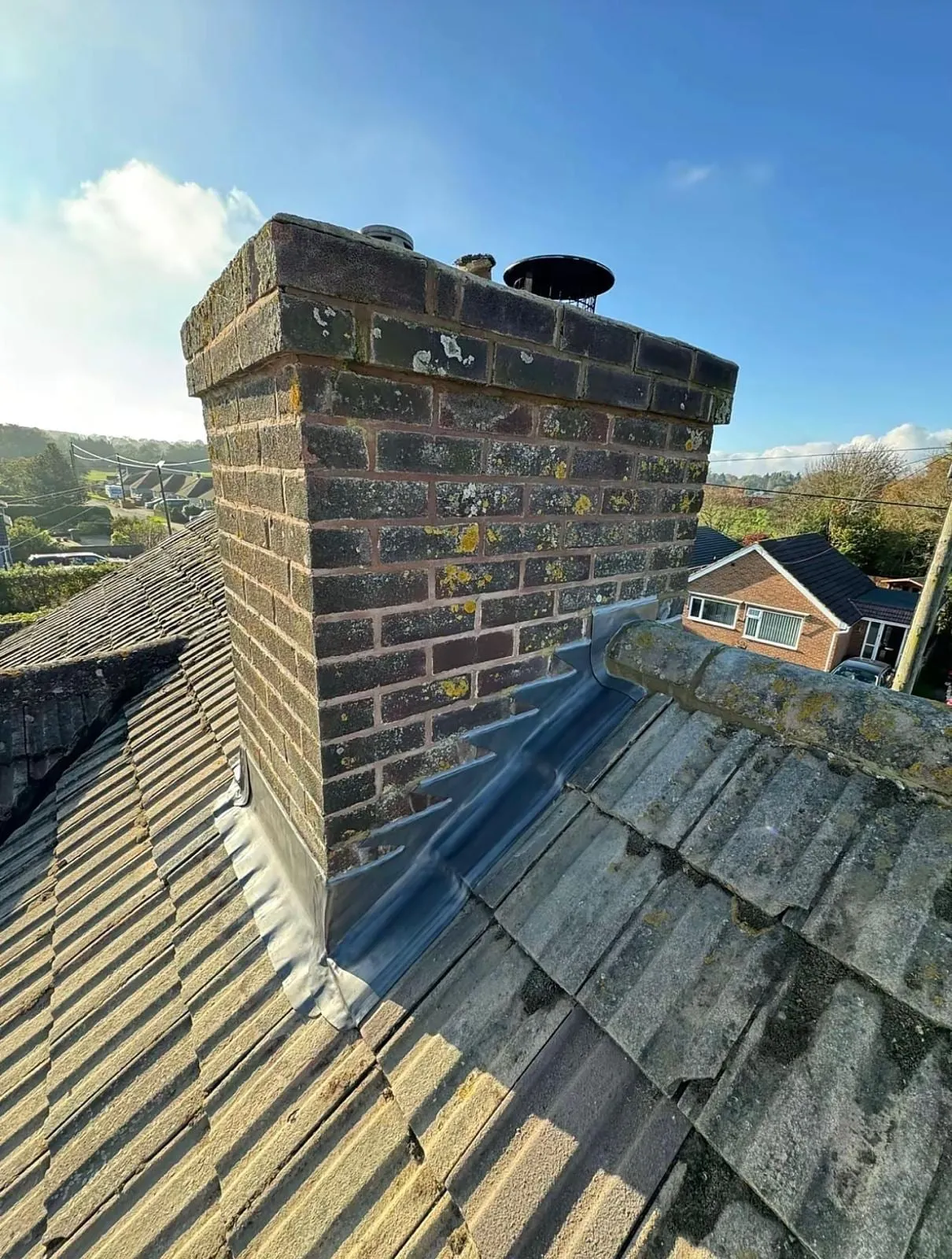 Brick chimney with lead flashing on a tiled roof