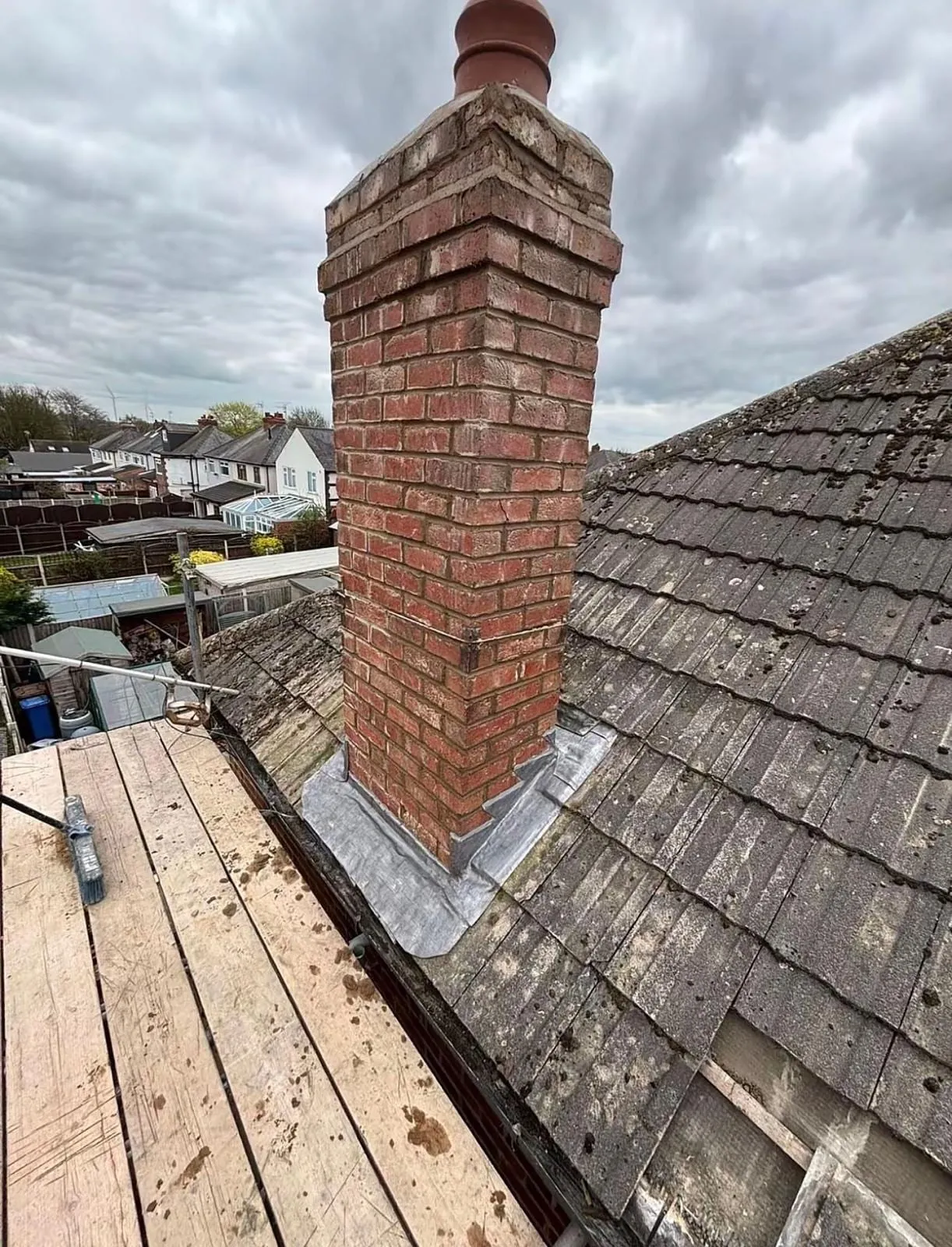 Brick chimney with lead flashing on a slate roof with scaffold