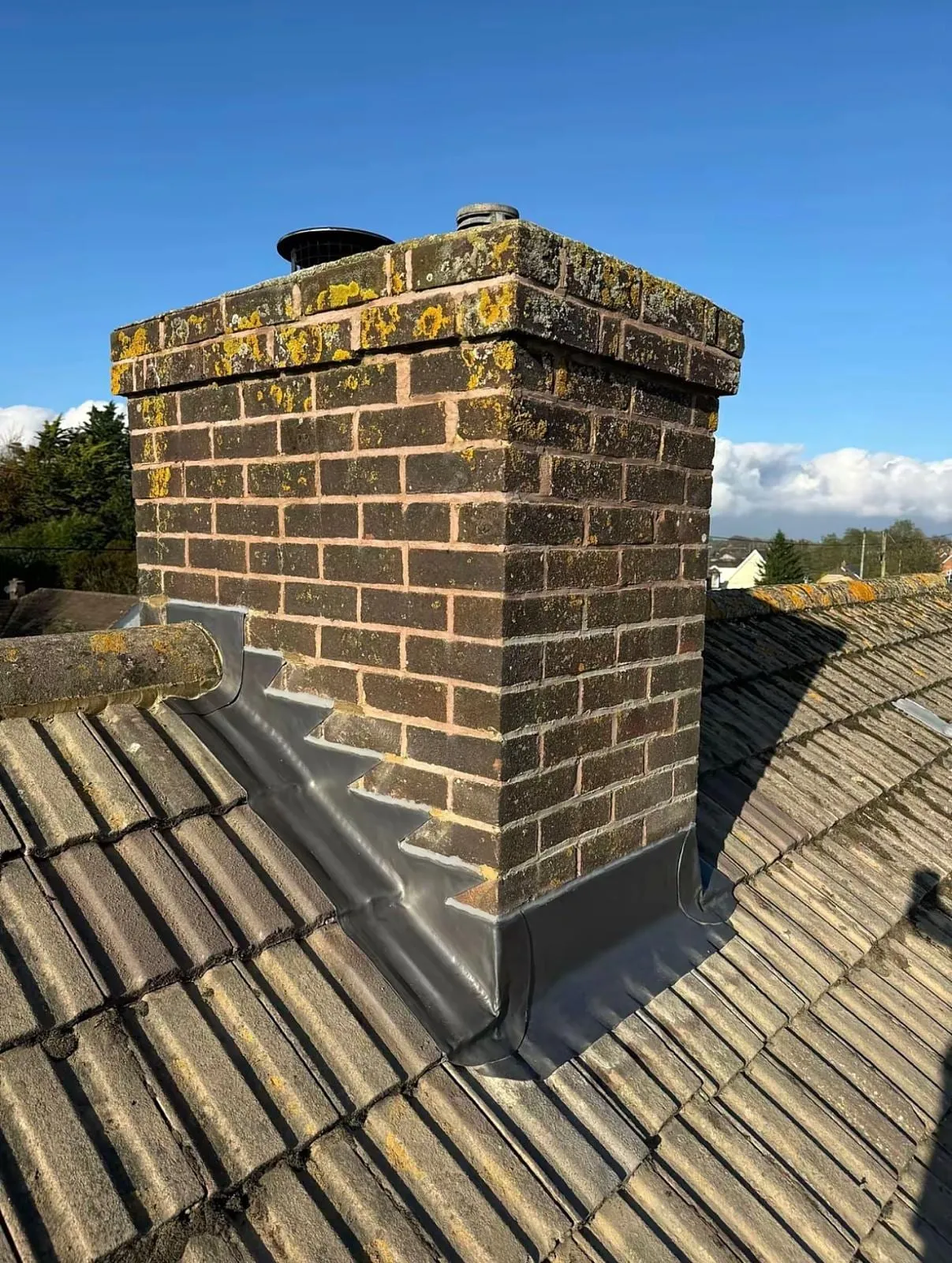 Chimney stack with stepped lead flashing on concrete tiles