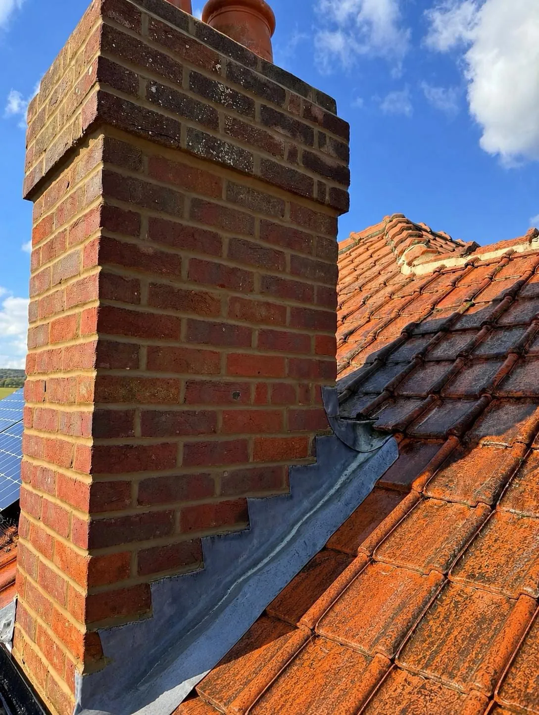 Brick chimney with stepped lead flashing and red tiles