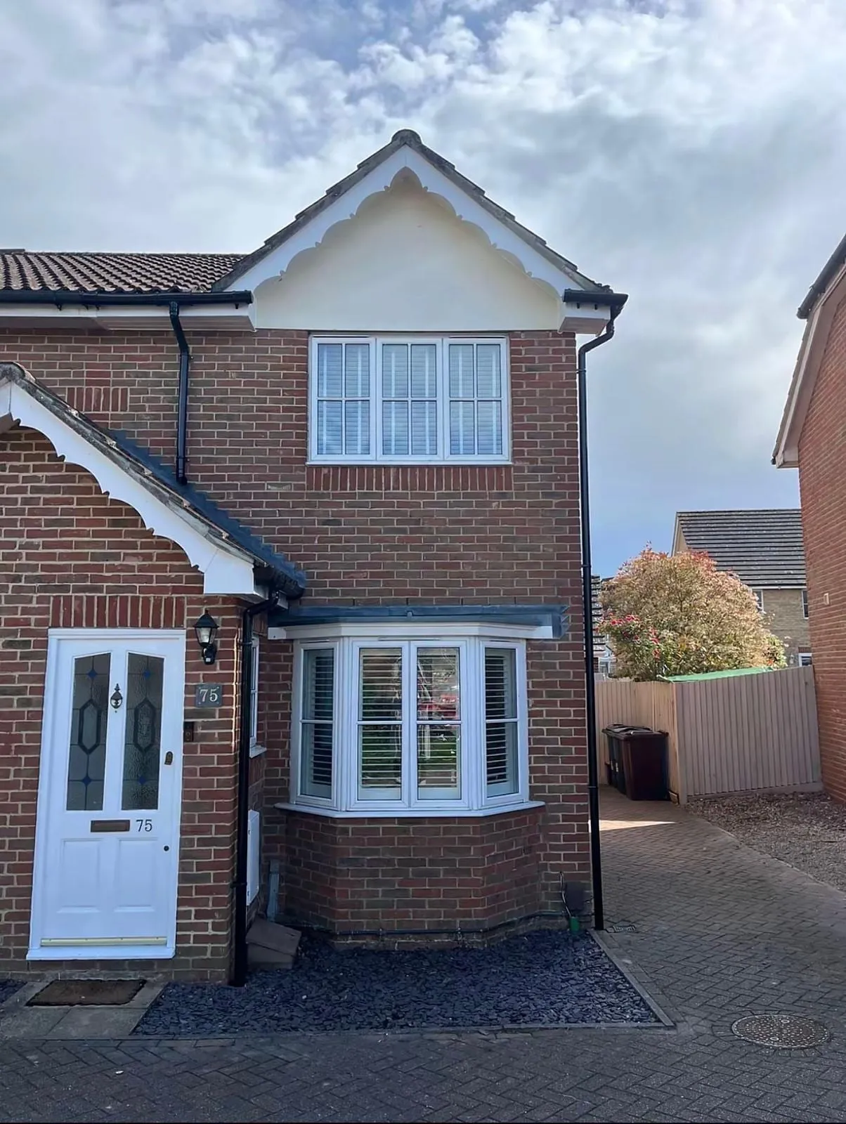 Detached brick house with white fascias and a bay window roof