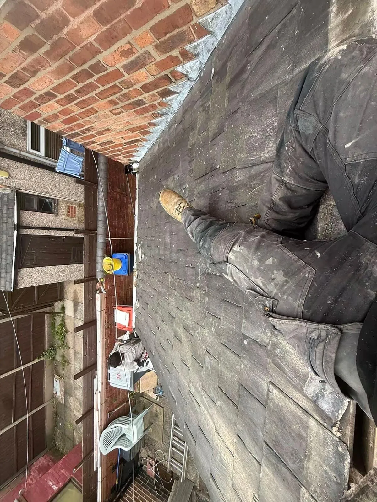 Roofer dressing lead flashing against a brick wall