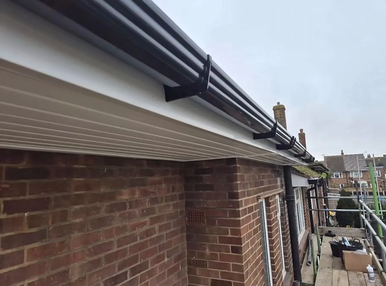 Fascia boards and dark guttering under scaffolding