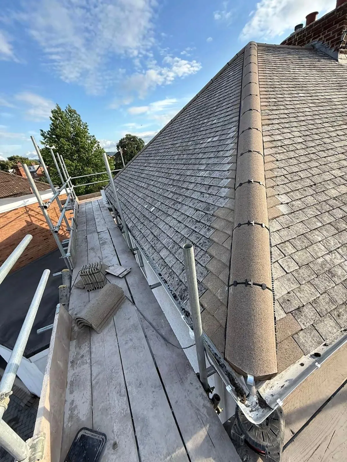 Grey slate roof with hip and ridge tiles and scaffold along the eaves