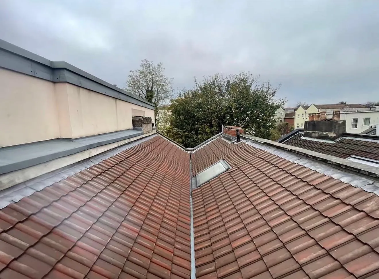Lead valley between two slopes of red tiles, with a rooflight and parapet wall