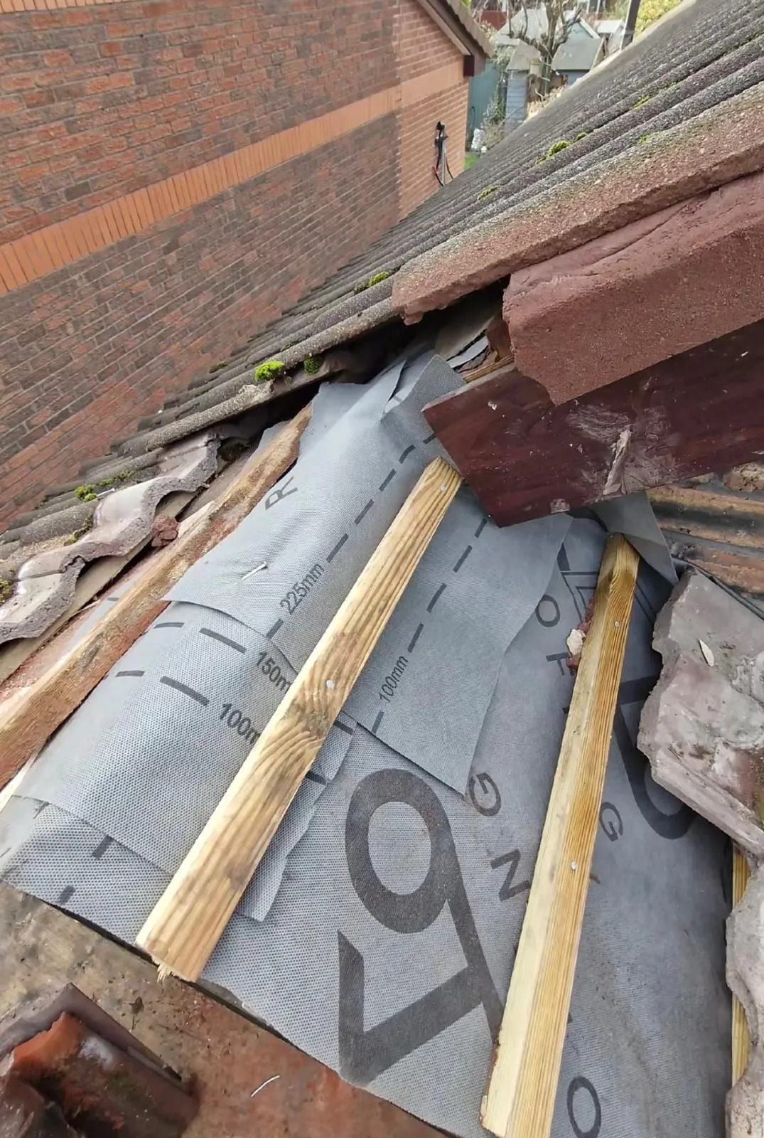 Membrane, battens and old tiles at the eaves beside a brick wall