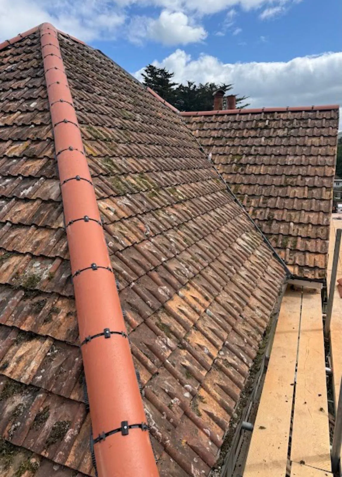New red ridge tiles along a hip on a tiled roof