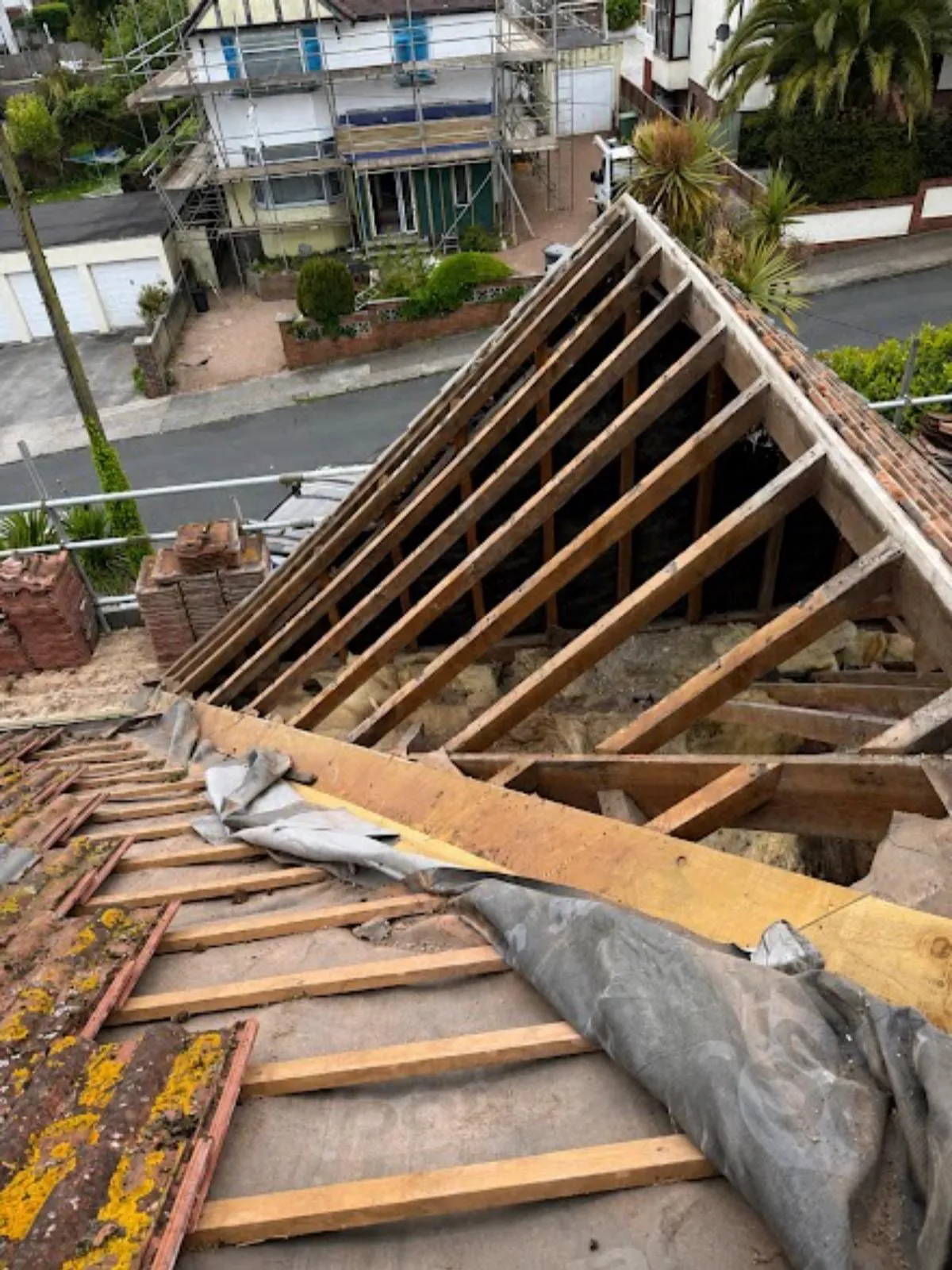 New roof timbers exposed on a hipped roof with a tarpaulin below