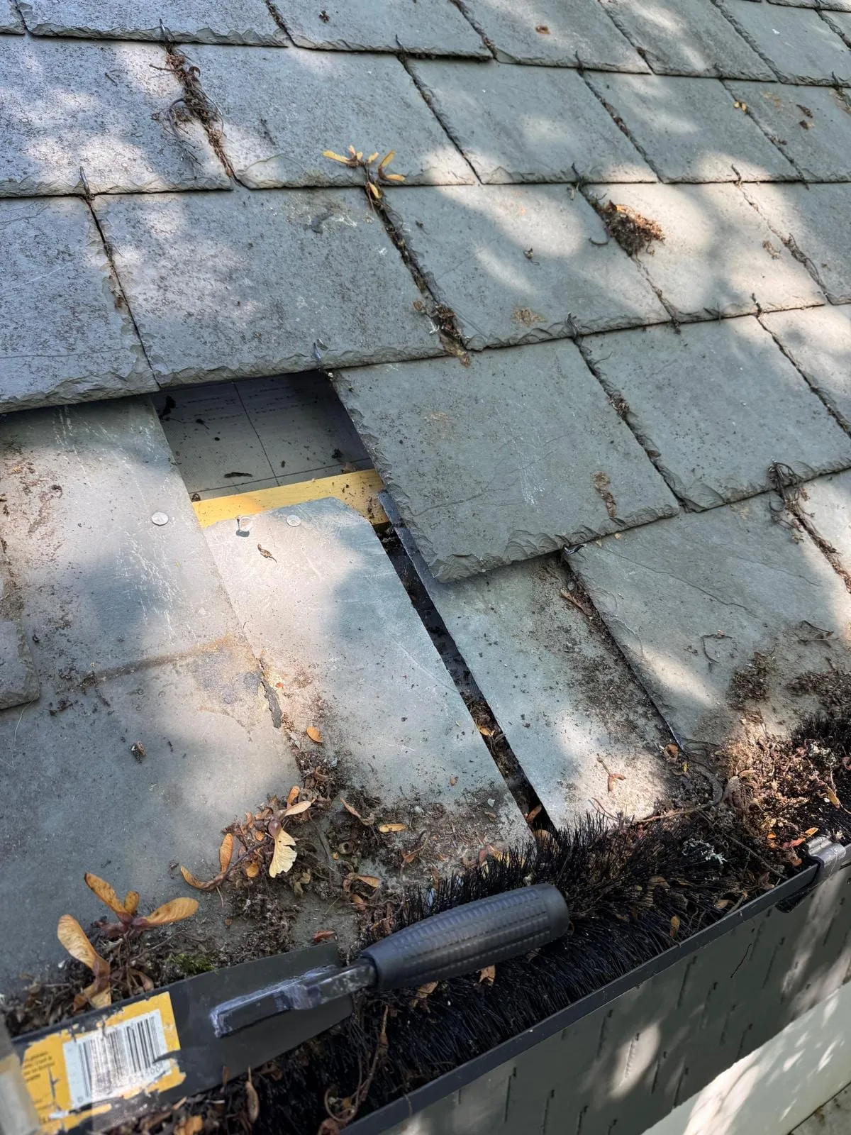 Replacing broken slates at the eaves, with debris in the gutter