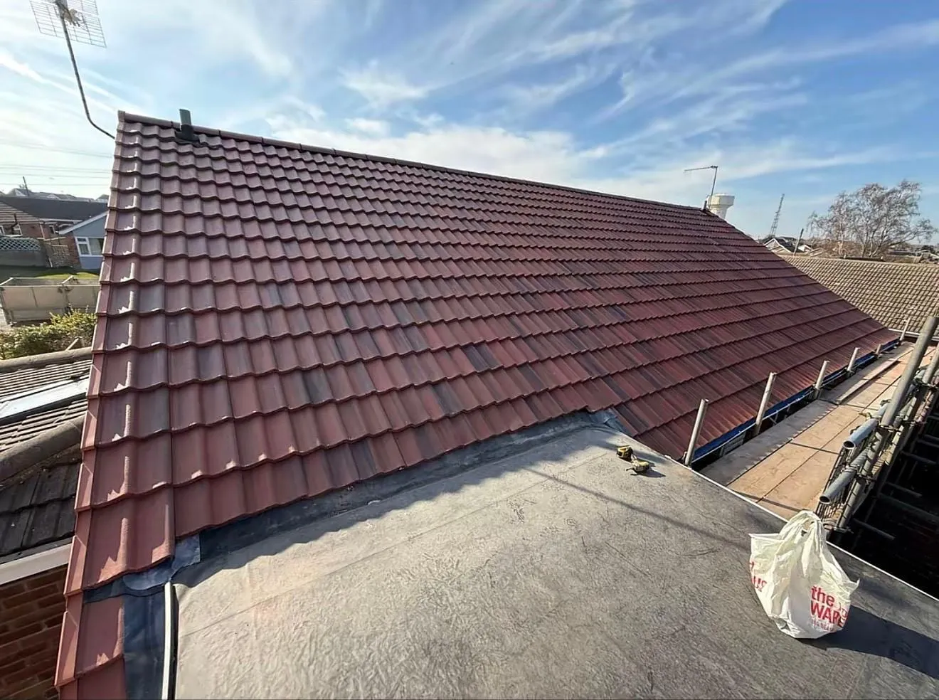 Dark red tiled roof with a flat roof section in the foreground