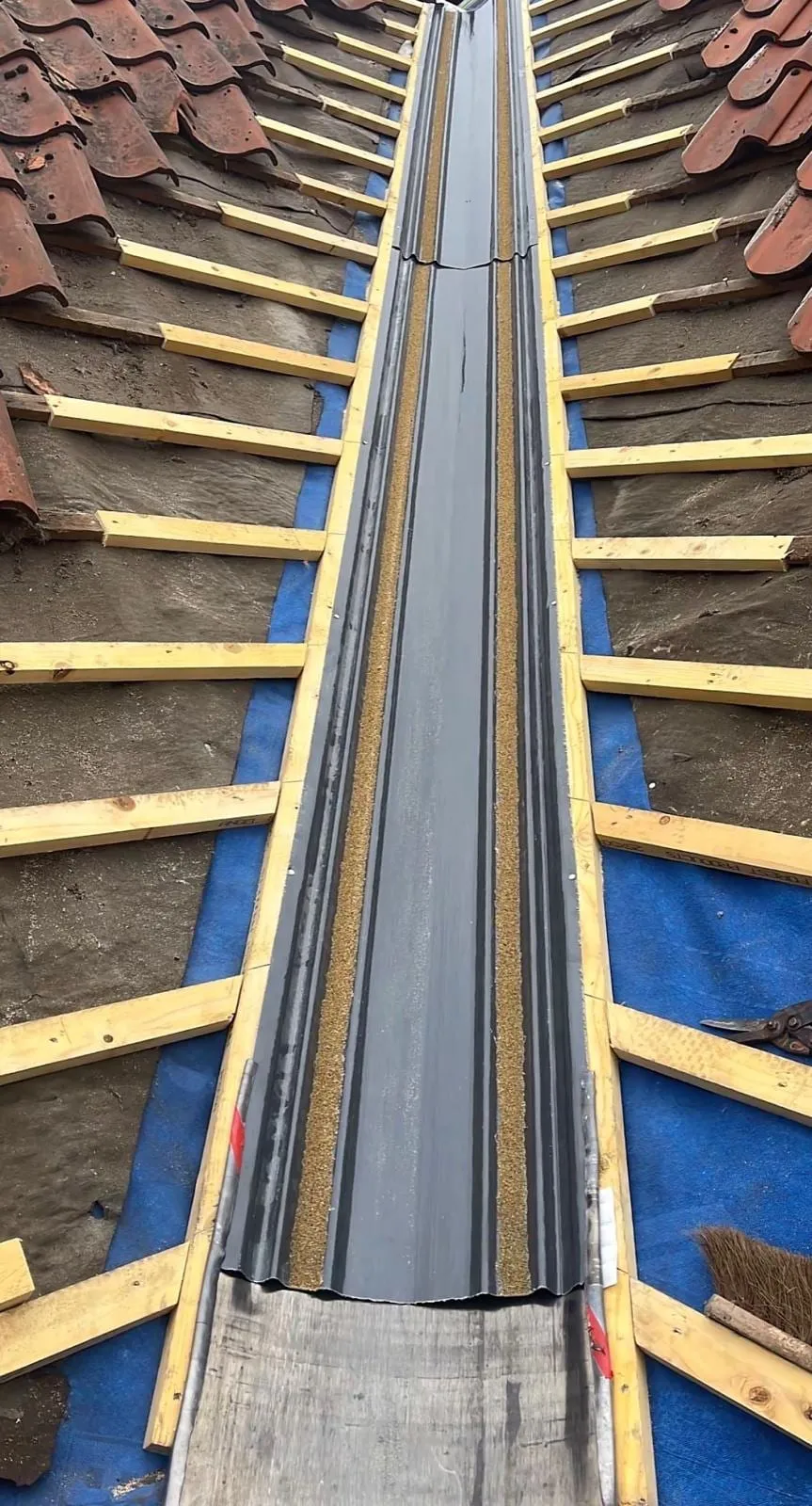New valley liner laid over membrane and battens between two tile slopes